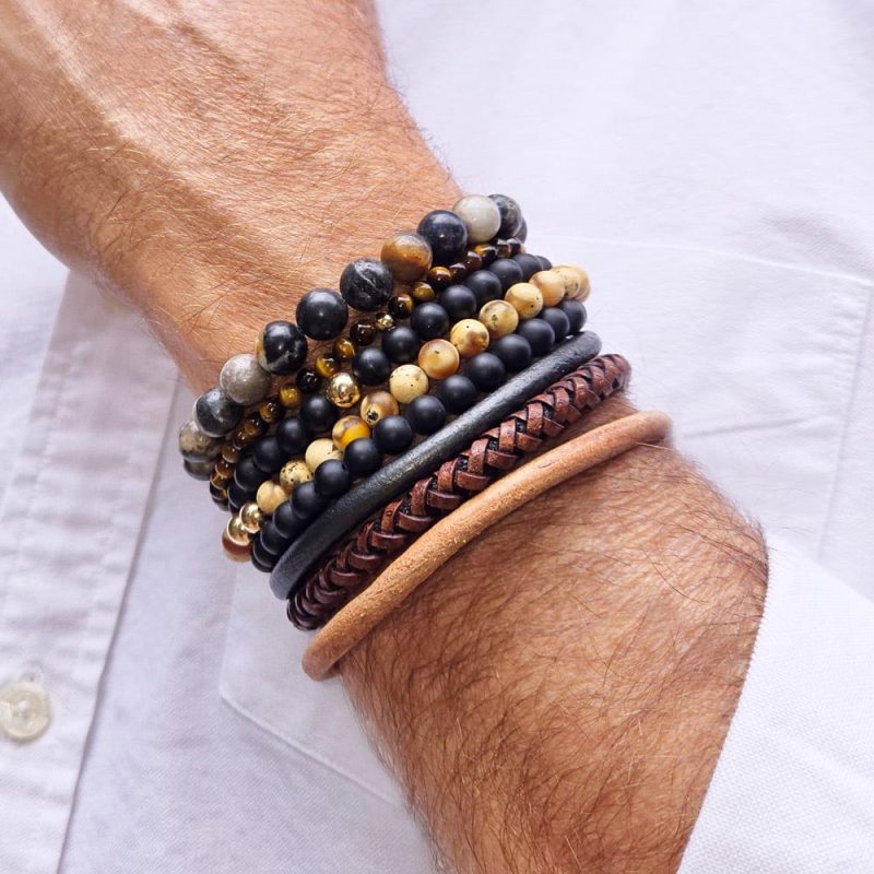 2 men s black onyx beaded bracelets stacked w 2 tiger s eye beaded bracelets w 14k gold beads w agate bead bracelet and brown and black leather bracelets white shirt