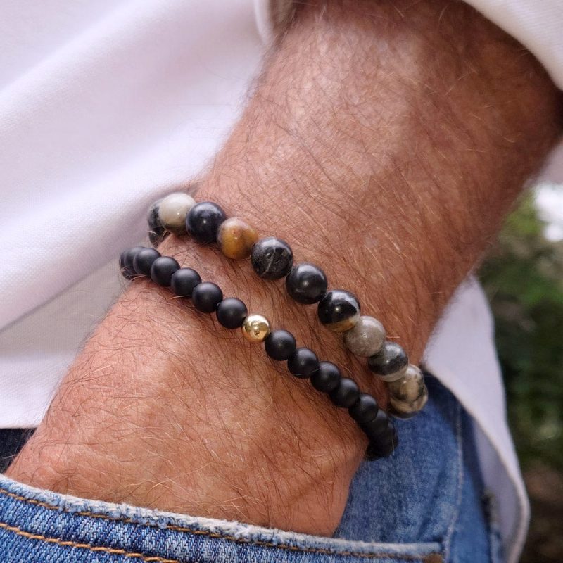 men s black onyx beaded bracelet w 14k gold bead next to grey gemstone bead bracelet white shirt denim